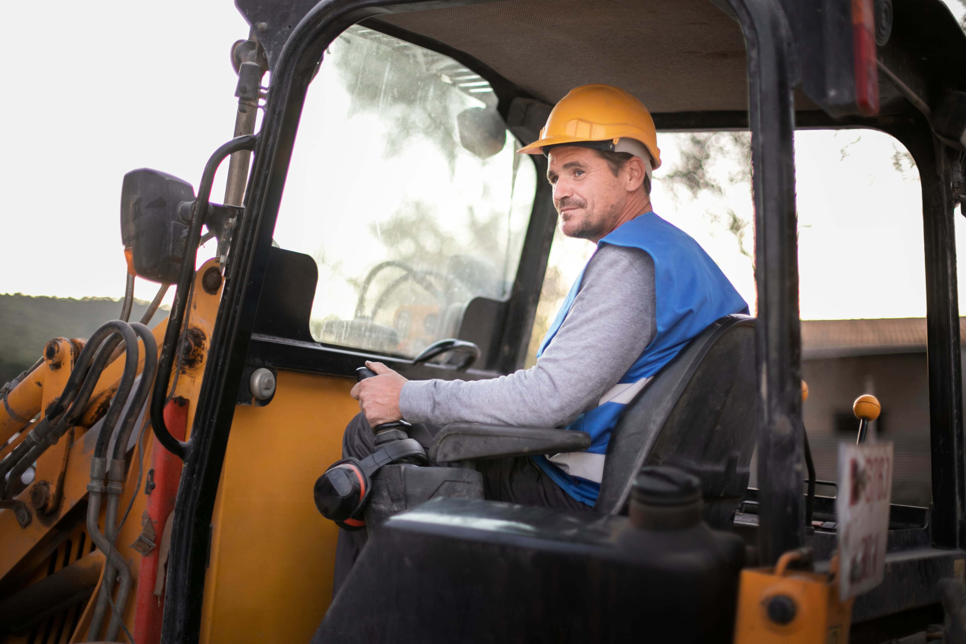 Operator in a hard hat inside heavy machinery